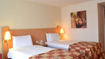 A hotel room with two beds, a nightstand, a lamp, and a painting on the wall.
