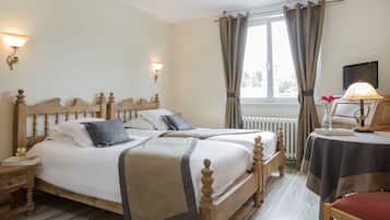 Ein Doppelbett mit Holz-Kopfteil, zwei Nachttische, ein kleiner Tisch mit Lampe und ein Fenster mit Vorhängen.