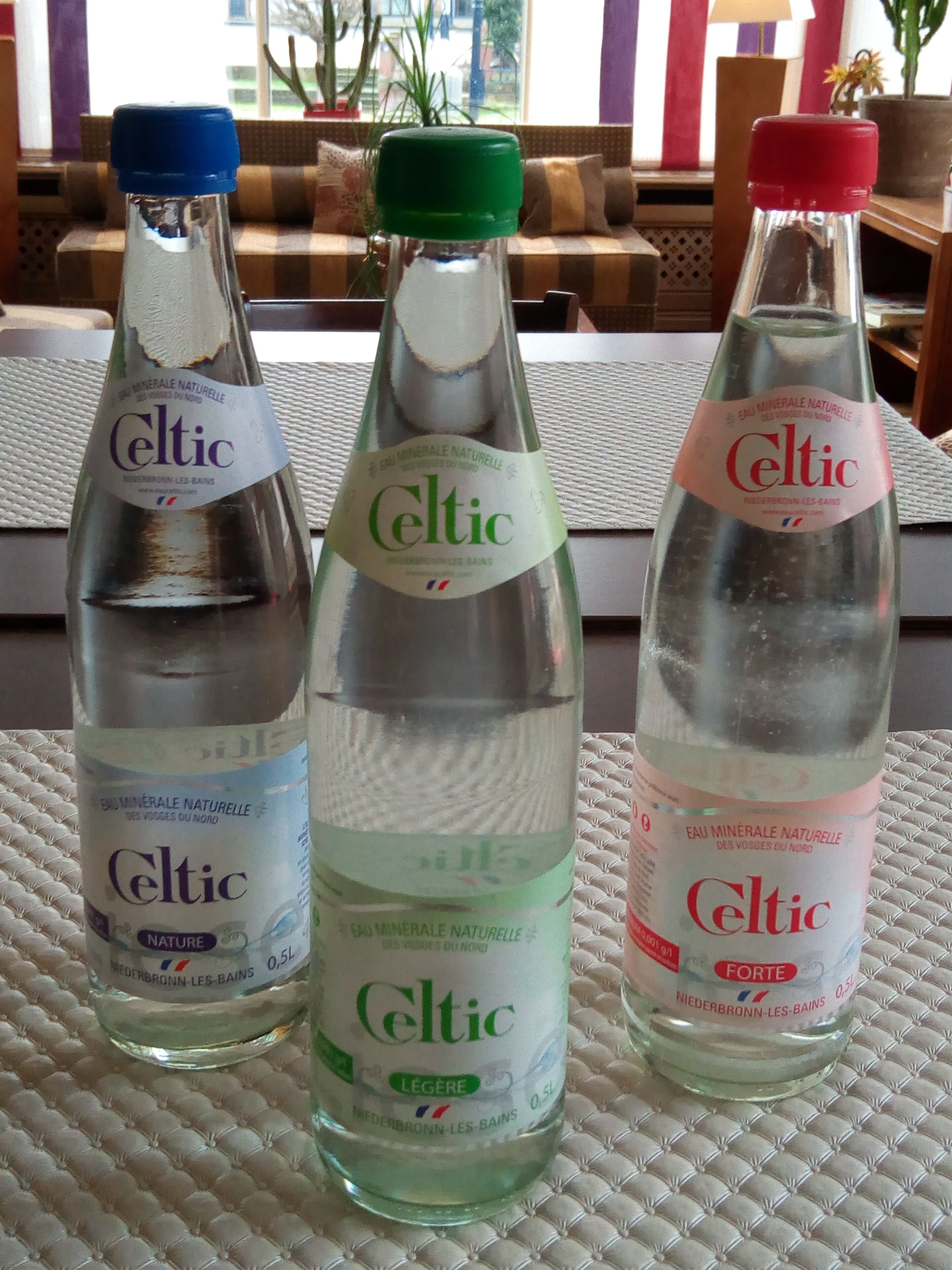 Três garrafas de água mineral Celtic sobre uma superfície texturizada.