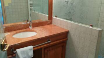 Un baño con lavamanos, espejo y ducha.
