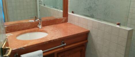 Un baño con lavamanos, espejo y ducha.