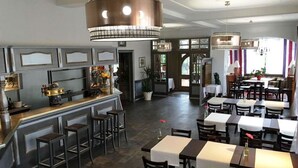 A restaurant with a bar area, multiple tables, and chairs. - Hotel Restaurant Le Bristol (Niederbronn-les-Bains)