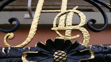 A decorative metal gate with a large, ornate letter 'H' and a floral design.