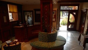 A lobby with a round seating area, a reception desk, and a view of the outdoors. - Hotel Restaurant Le Bristol (Niederbronn-les-Bains)