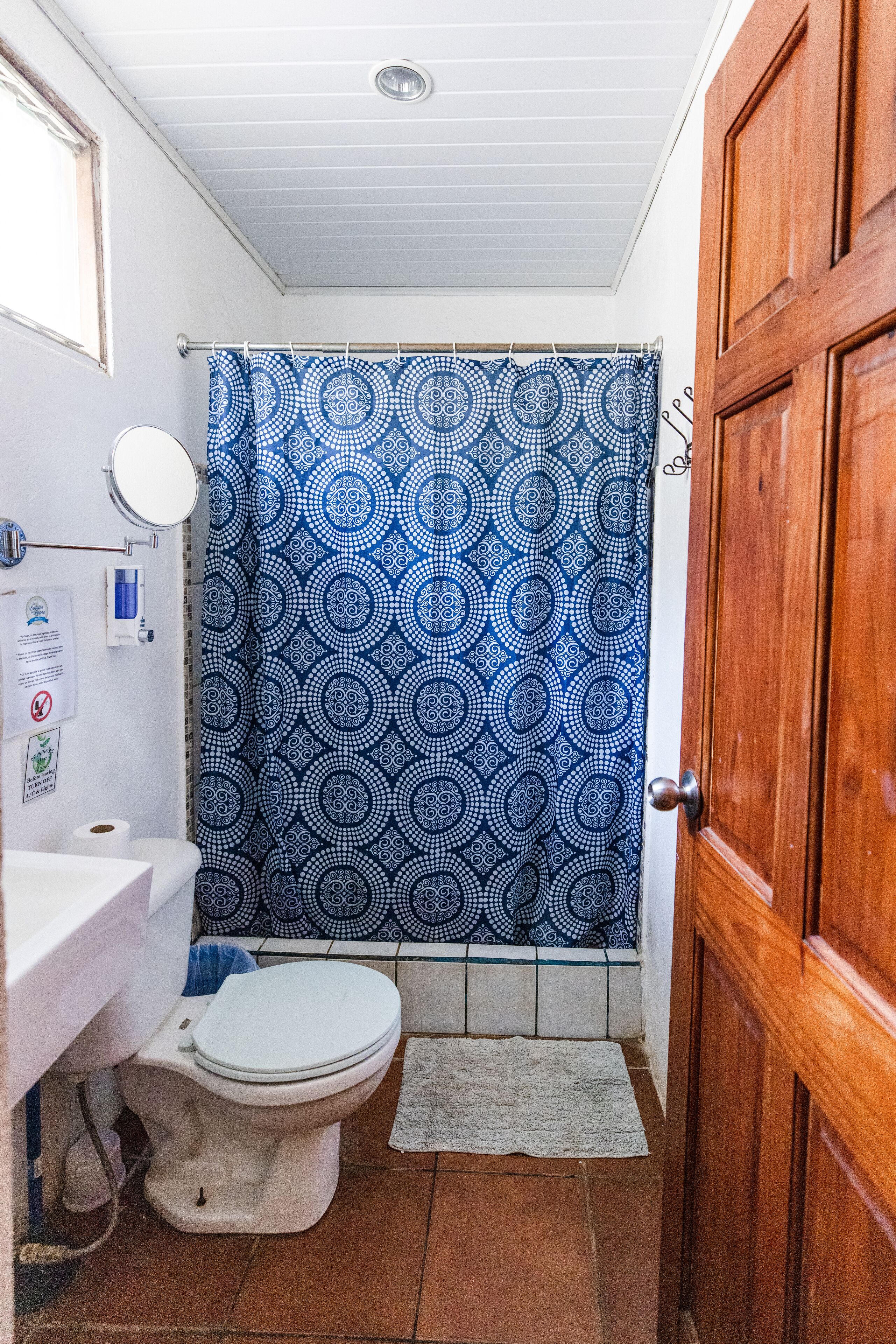 A compact bathroom with a white toilet, a sink, and a shower curtain with a geometric pattern.