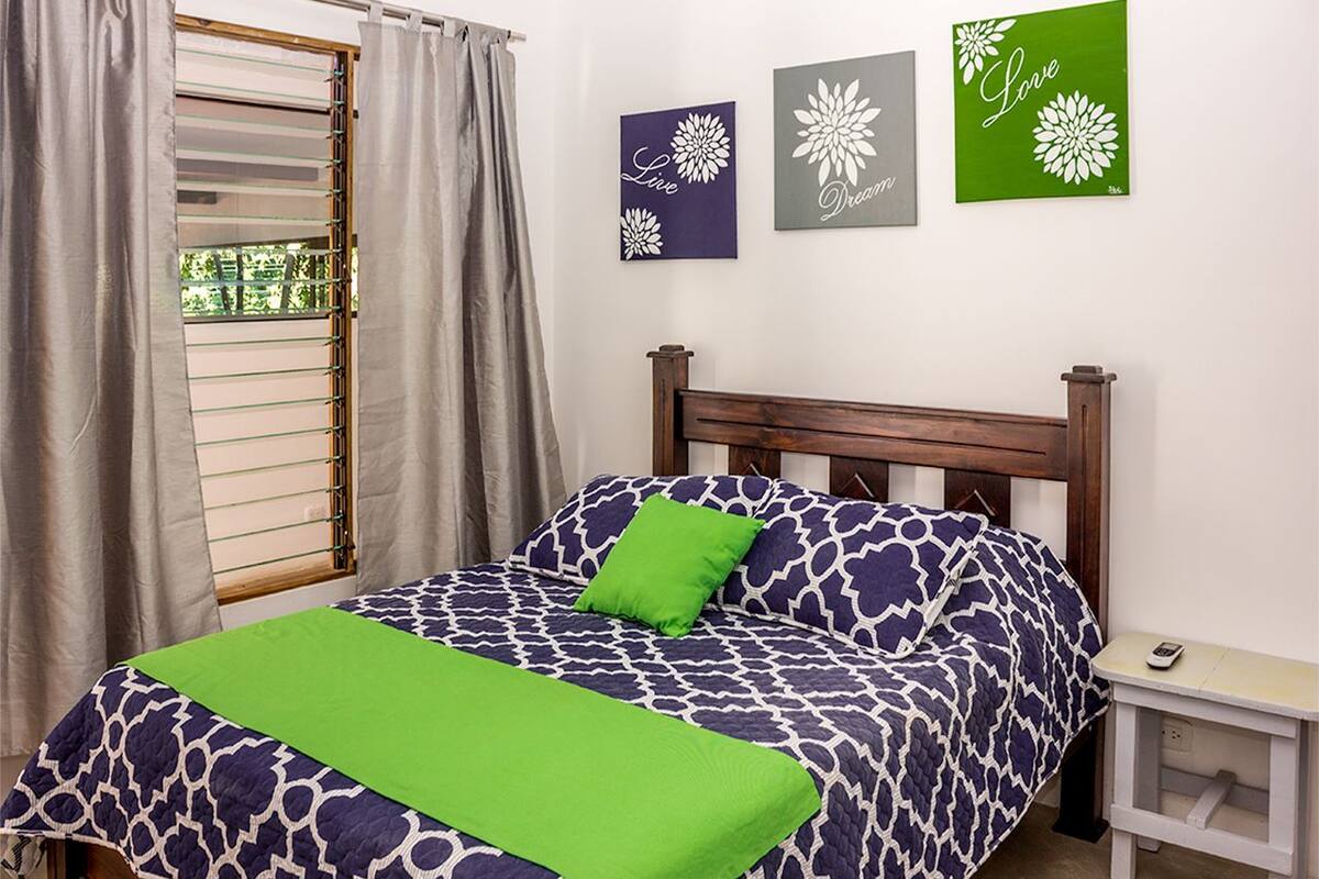 A bedroom with a bed, a nightstand, and a window with curtains.
