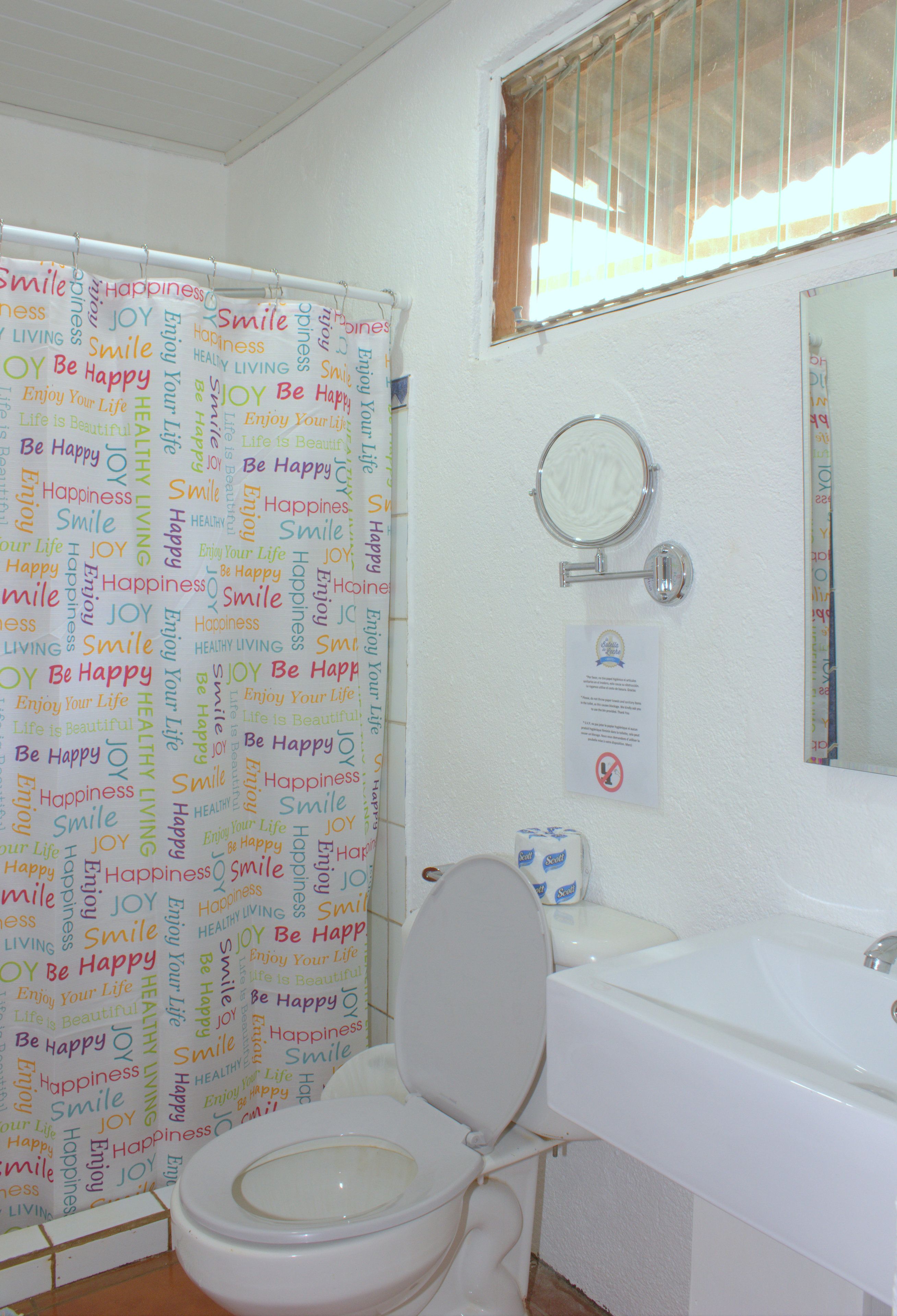 A bathroom with a toilet, sink, and shower curtain with motivational words.