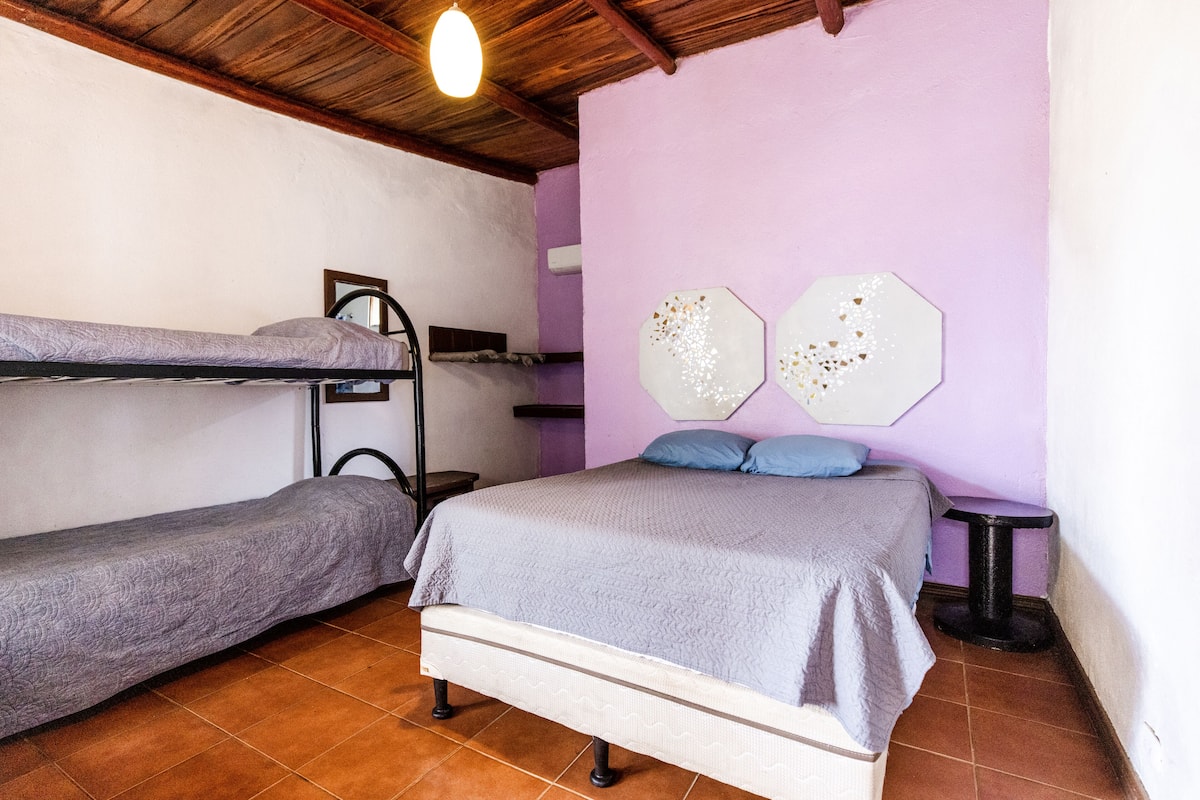 A bedroom with two bunk beds, a single bed, and a small table.