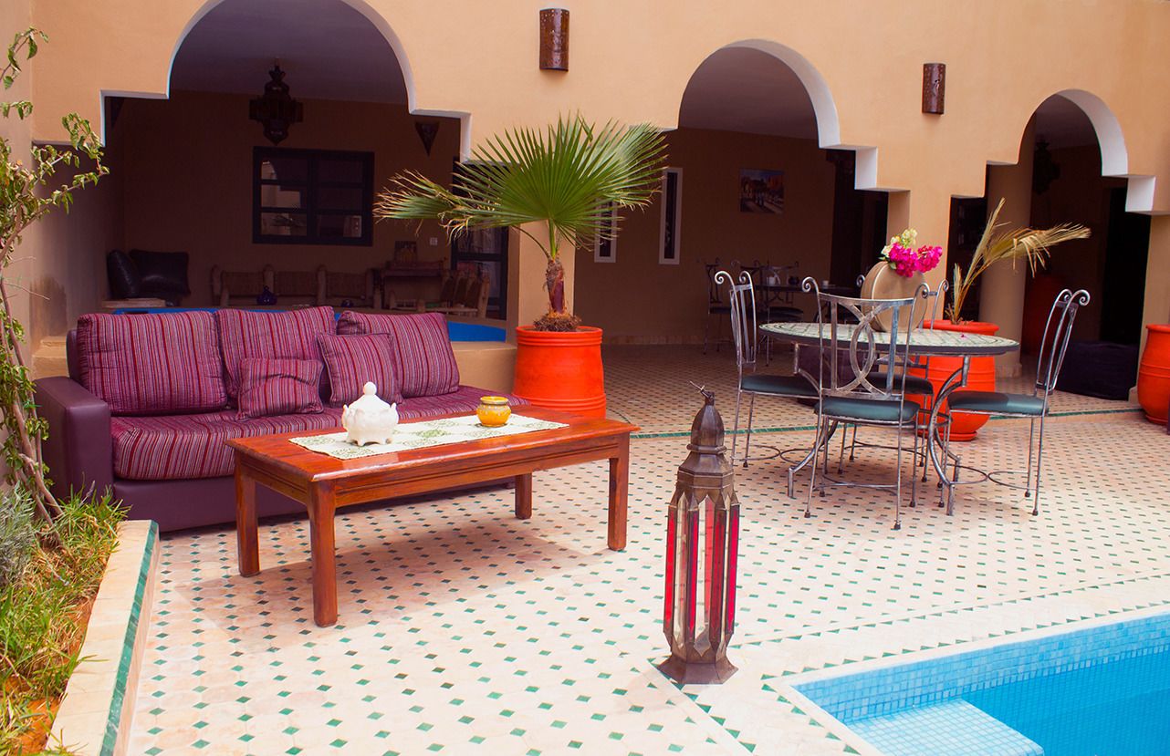 Cómodo espacio al aire libre con piscina, que incluye un sofá, mesa, sillas y plantas en macetas.