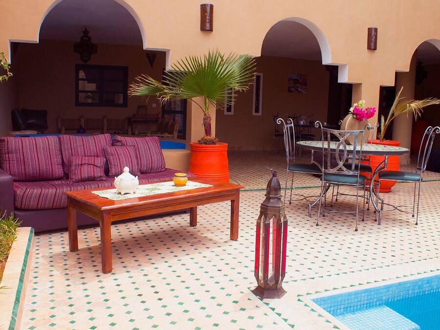 Cómodo espacio al aire libre con piscina, que incluye un sofá, mesa, sillas y plantas en macetas.