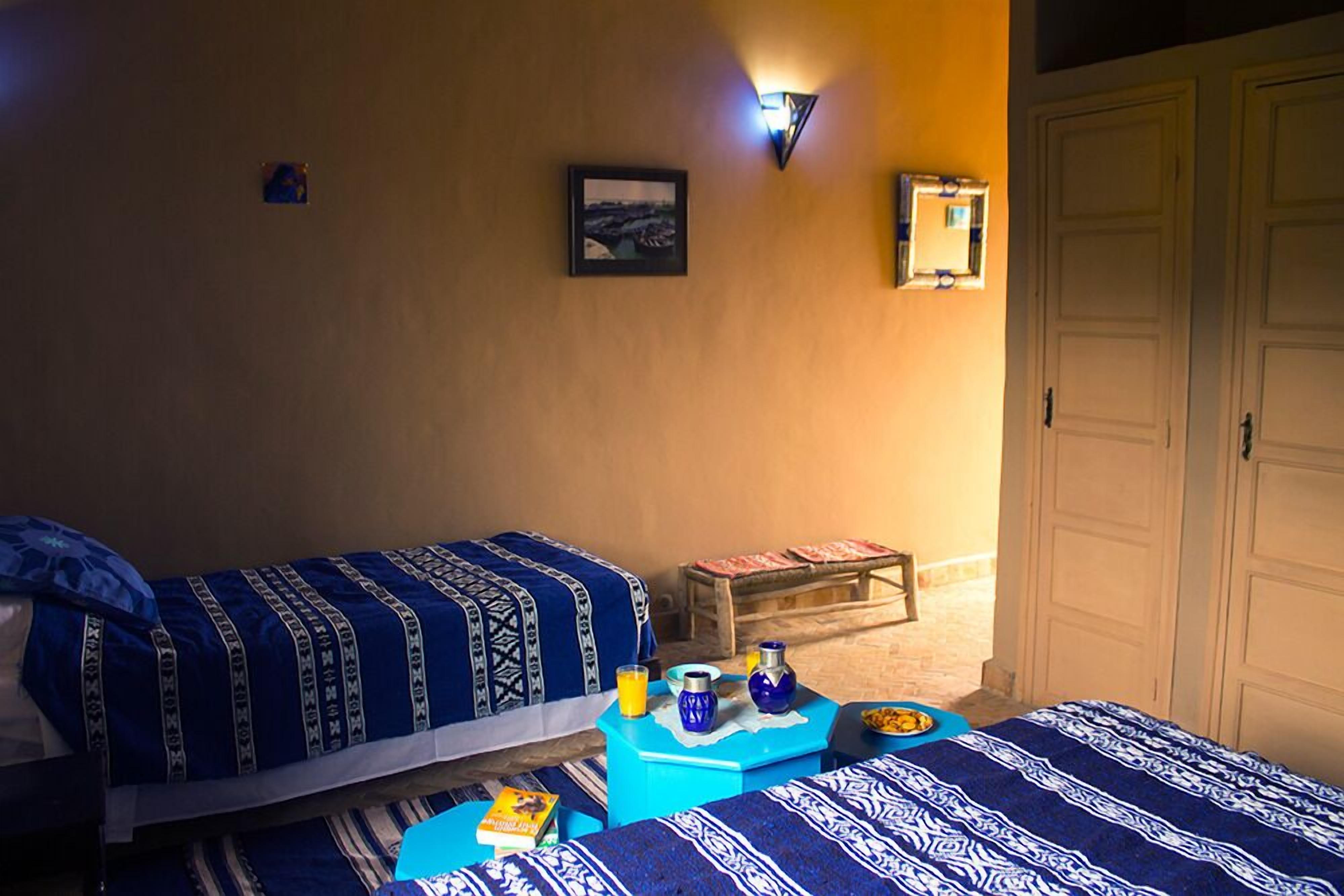 Ein Zimmer mit zwei Betten, einem kleinen Tisch mit Frühstücksangeboten und einer Wandleuchte.