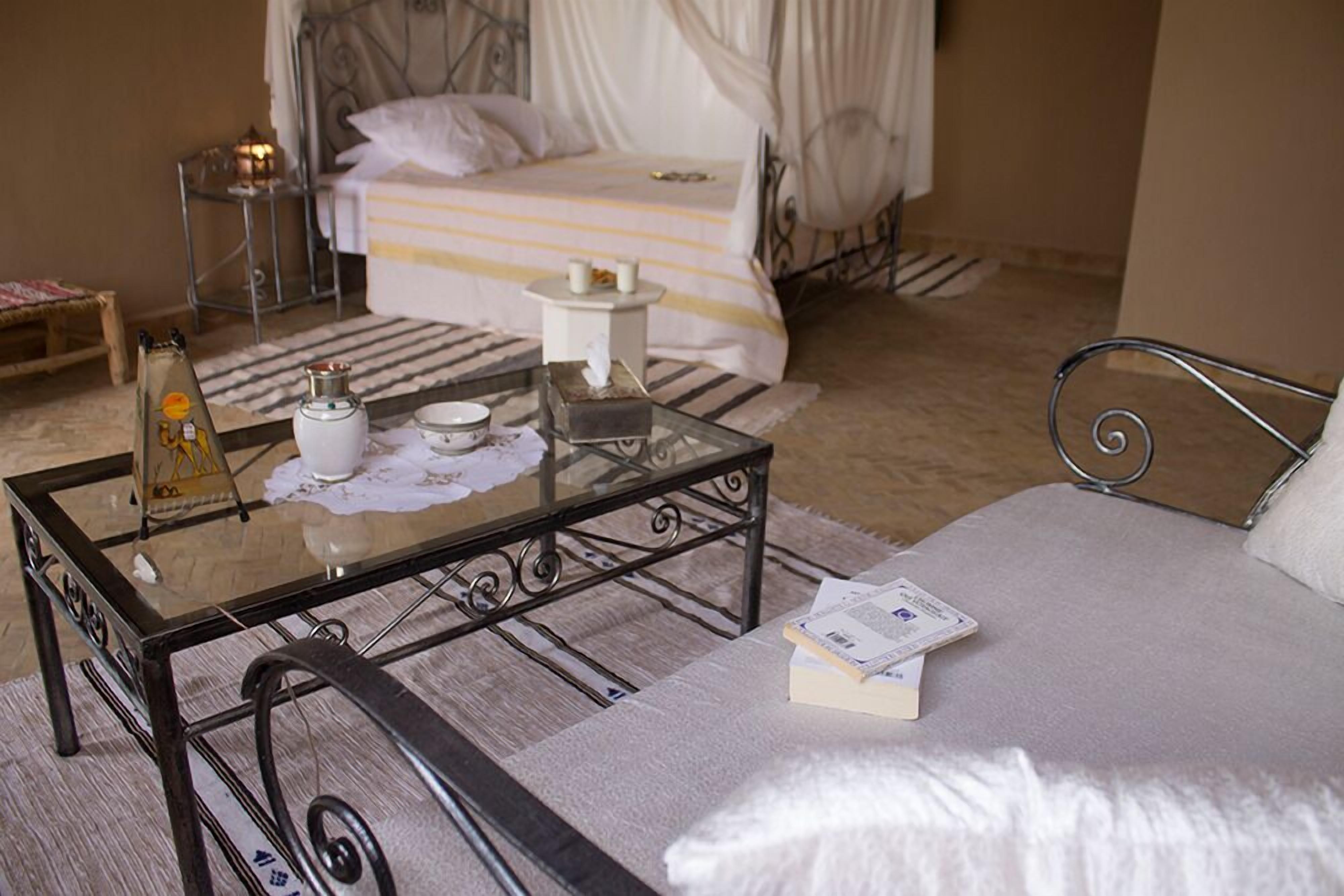 A neatly arranged bedroom with a bed, bedside table, and a glass coffee table.