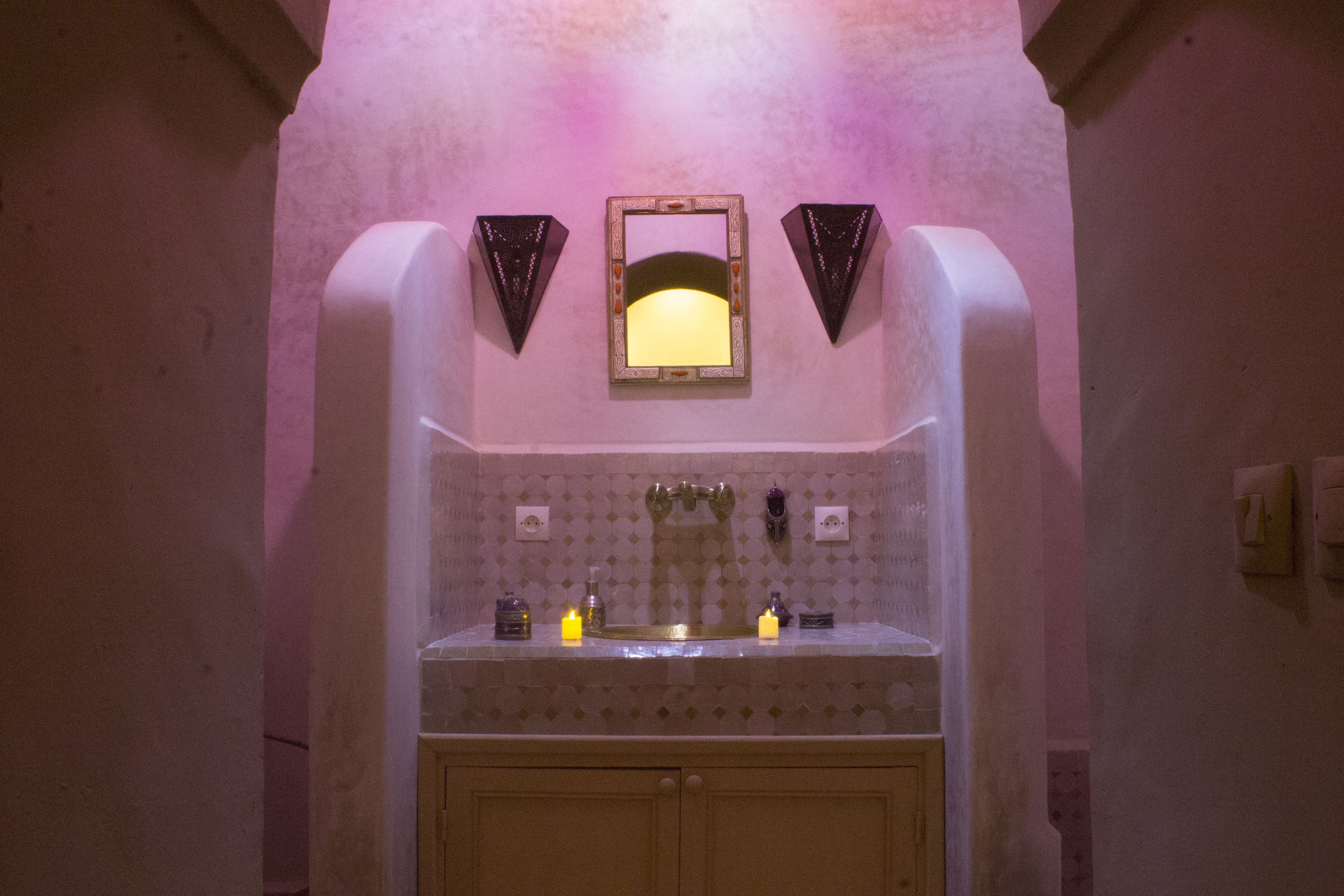 A bathroom with a sink, mirror, and two wall-mounted lights.