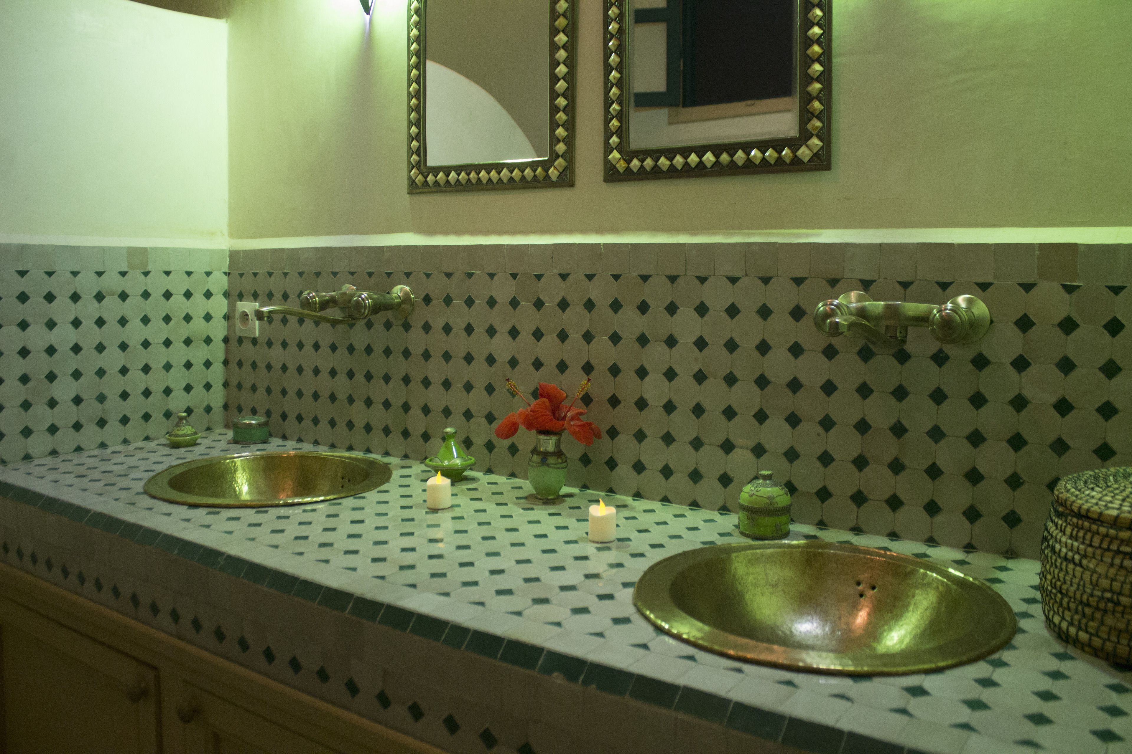 Une salle de bain avec deux lavabos, un miroir et des objets décoratifs posés sur le comptoir.