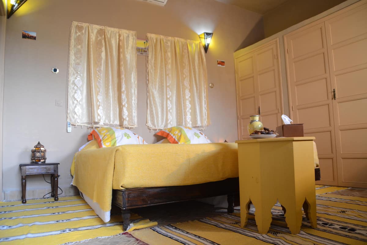 A bedroom with a bed, a nightstand, a table, and a wardrobe.