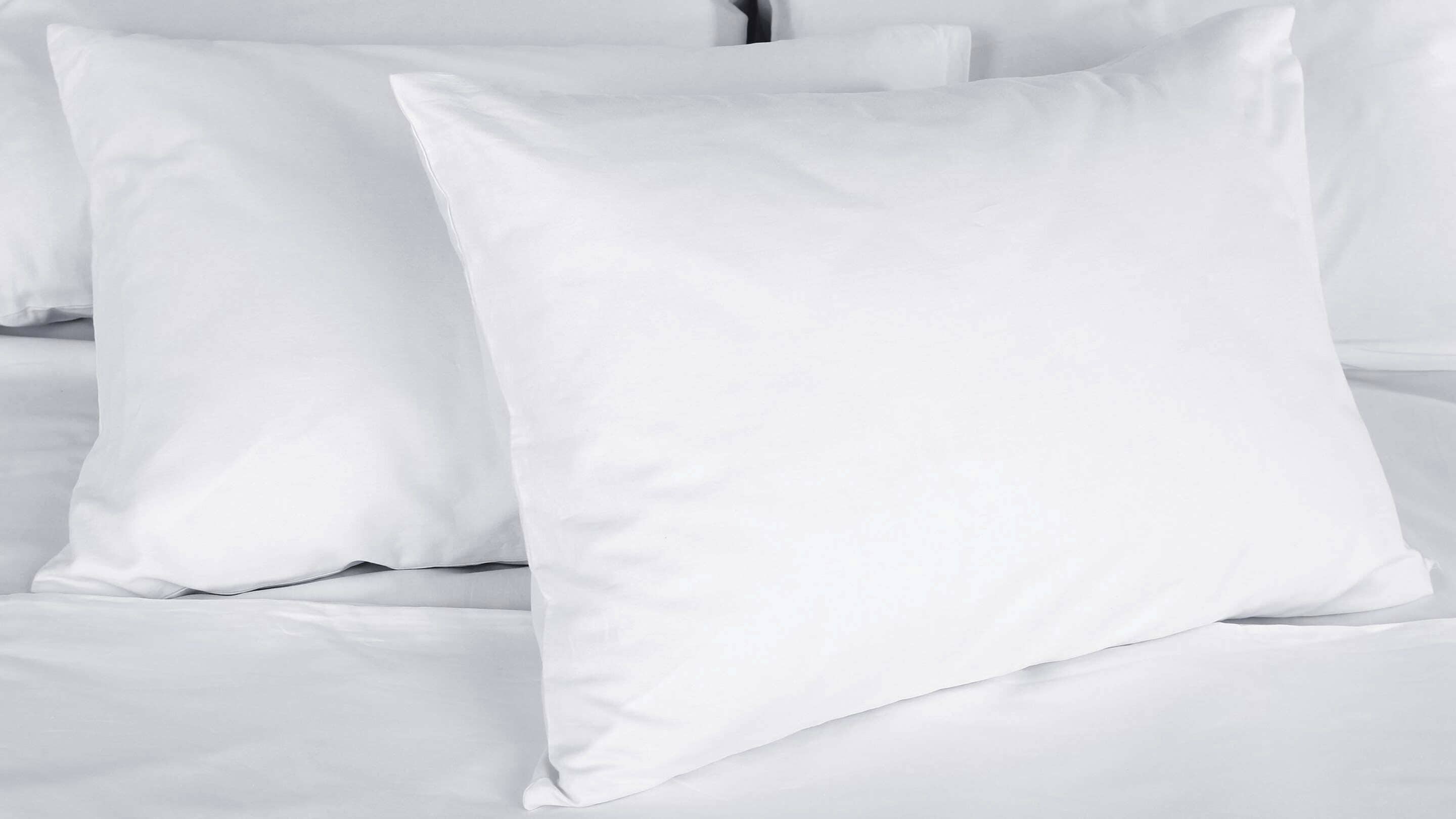 Una cama con ropa de cama y almohadas blancas.
