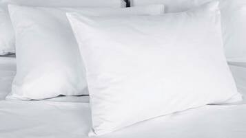 Una cama con ropa de cama y almohadas blancas.