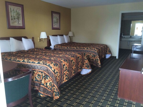 A hotel room with two beds, a desk, a chair, and two wall-mounted lamps. - Executive Inn & Suites Schulenburg (Schulenburg)