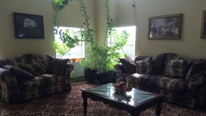 A living room with two sofas, a coffee table, and potted plants. - Executive Inn & Suites Schulenburg (Schulenburg)