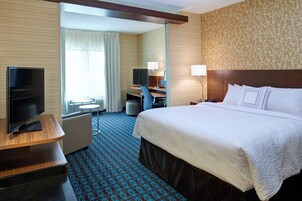 Una habitación de hotel con cama, escritorio, televisión y zona de estar.