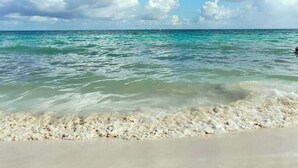 A beach with clear turquoise water, white sand, and a partly cloudy sky. - Fiesta Inn Playa del Carmen (Playa del Carmen)