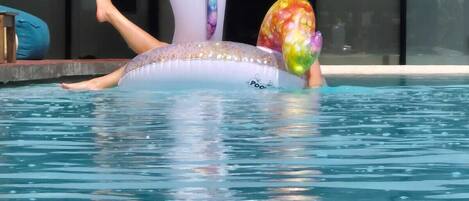 A person lying on a unicorn-shaped inflatable in a swimming pool.