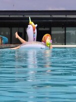 Una persona recostada sobre un flotador con forma de unicornio en una piscina.