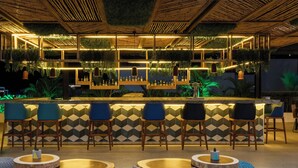 A bar area with a geometric patterned wall, wooden ceiling, and hanging plants. - Fiesta Inn Playa del Carmen (Playa del Carmen)