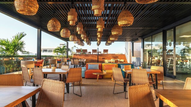 An outdoor seating area with wicker furniture and hanging wicker lamps. - Fiesta Inn Playa del Carmen (Playa del Carmen)