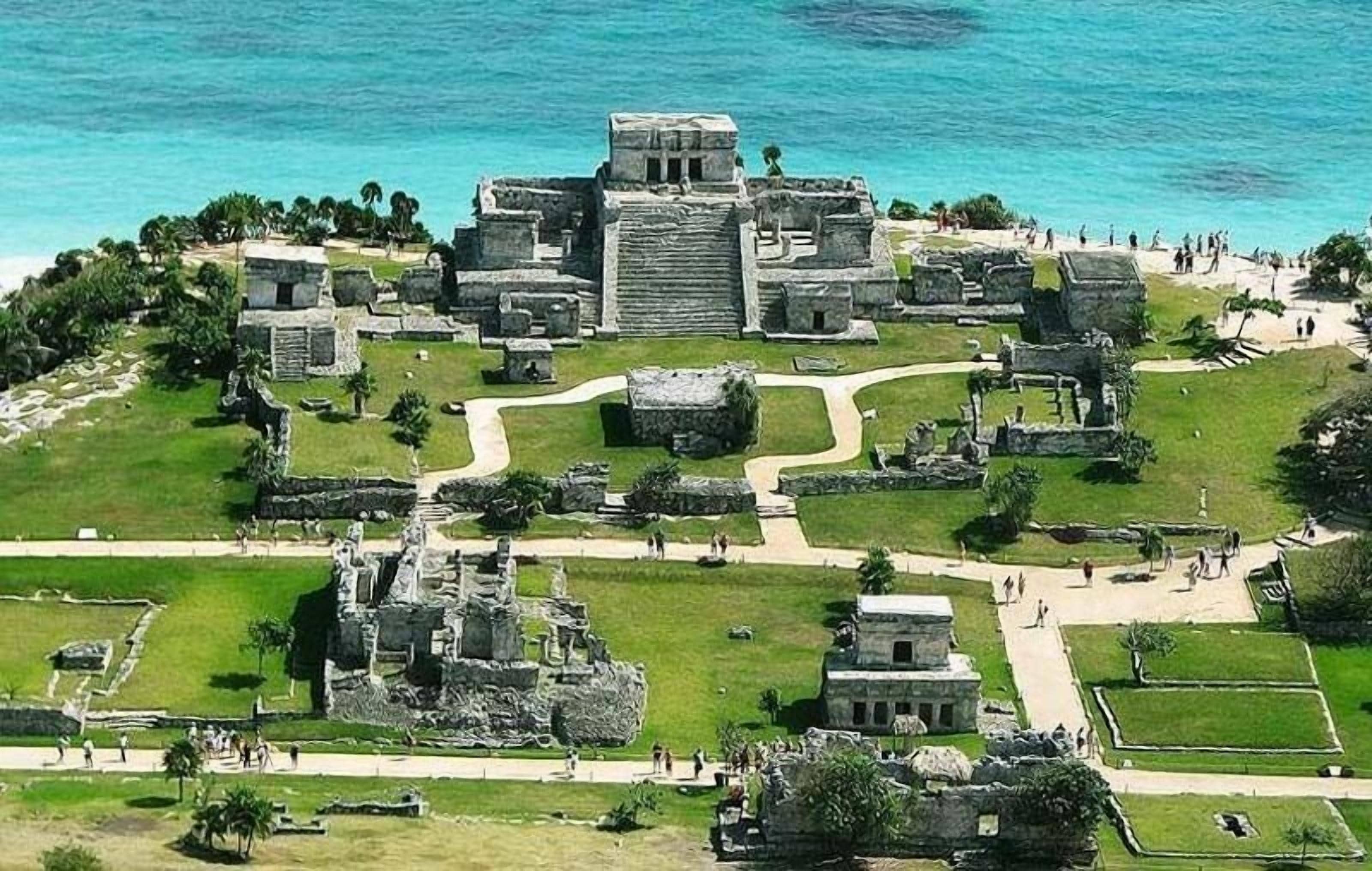 An aerial view of a historical site with ruins and pathways, surrounded by water and greenery.
