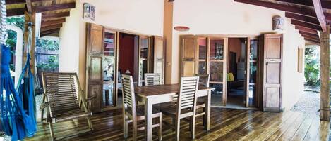 A wooden dining area with a table and chairs, a ceiling fan, and wooden cabinets with glass doors.