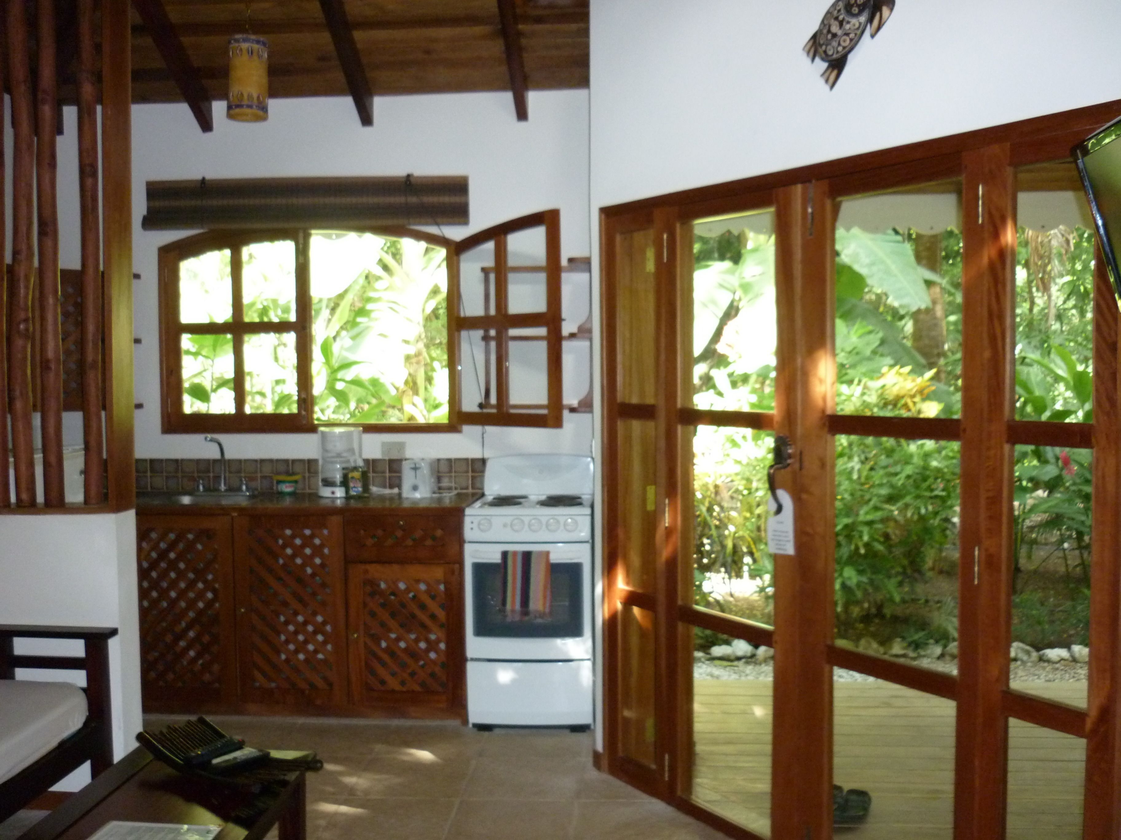 A kitchen with wooden cabinets, a stove, and a window overlooking greenery.