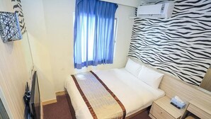 A hotel room with a bed, a nightstand, a TV, a window with curtains, and a zebra-patterned wall. - Da San Tong Hotel (Chiayi City)
