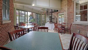 A restaurant with brick walls, wooden tables, and chairs. There is a staircase leading to an upper level. - The Lincklaen House (Cazenovia)