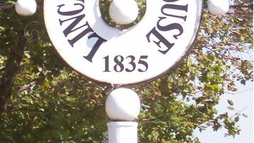 Een rond bord met de tekst 'Lindzen House 1835' op een paal bevestigd.