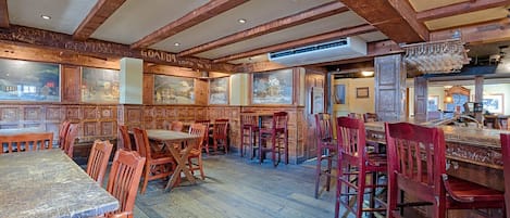 A restaurant with wooden beams, rustic decor, and multiple seating areas.