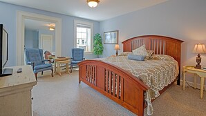 A bedroom with a wooden bed, two chairs, a desk, a lamp, and a television. - The Lincklaen House (Cazenovia)