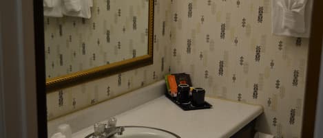 Et badeværelse med vask, spejl og toiletartikler.