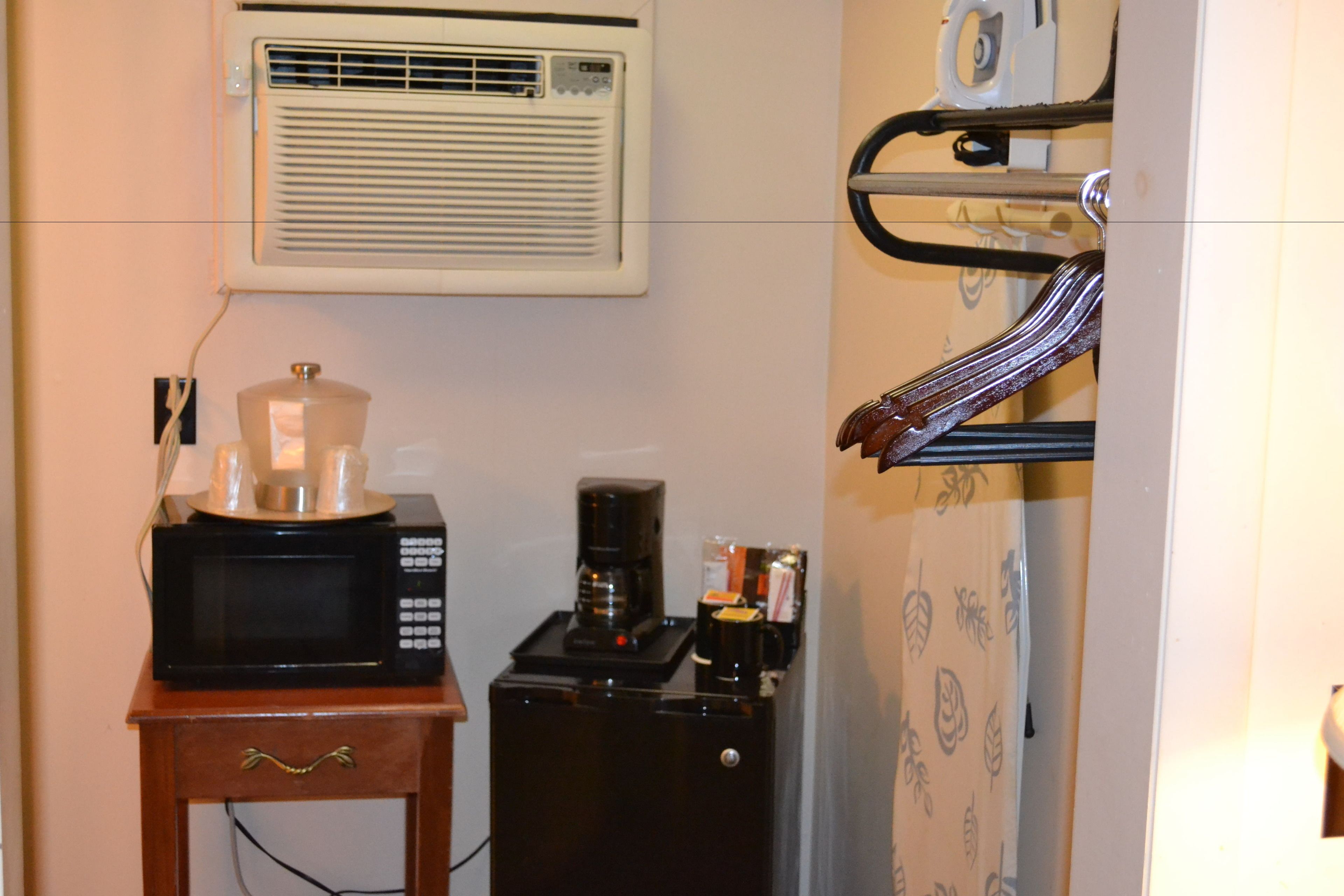 Una kitchenette compacta con microondas, cafetera y un refrigerador pequeño.