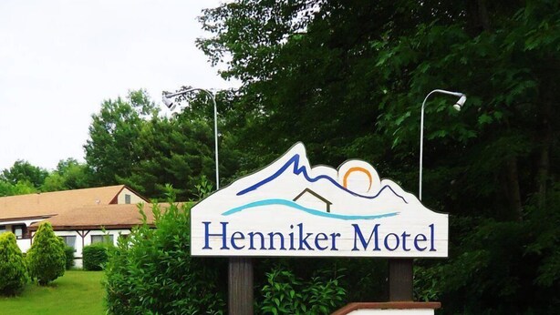 A sign for the Henniker Motel with a mountain and sun graphic. - Henniker Motel (Henniker)