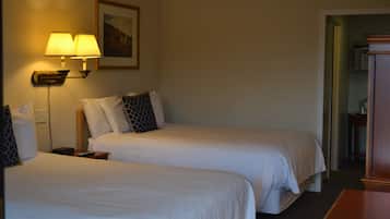 Ein Hotelzimmer mit zwei Betten, einem Nachttisch mit Lampe, einem Bild an der Wand und einem Holztisch.