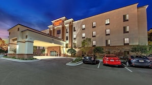 A hotel with a modern design, featuring a prominent entrance and a parking lot with several cars. - Hampton Inn Summerville SC (Summerville)
