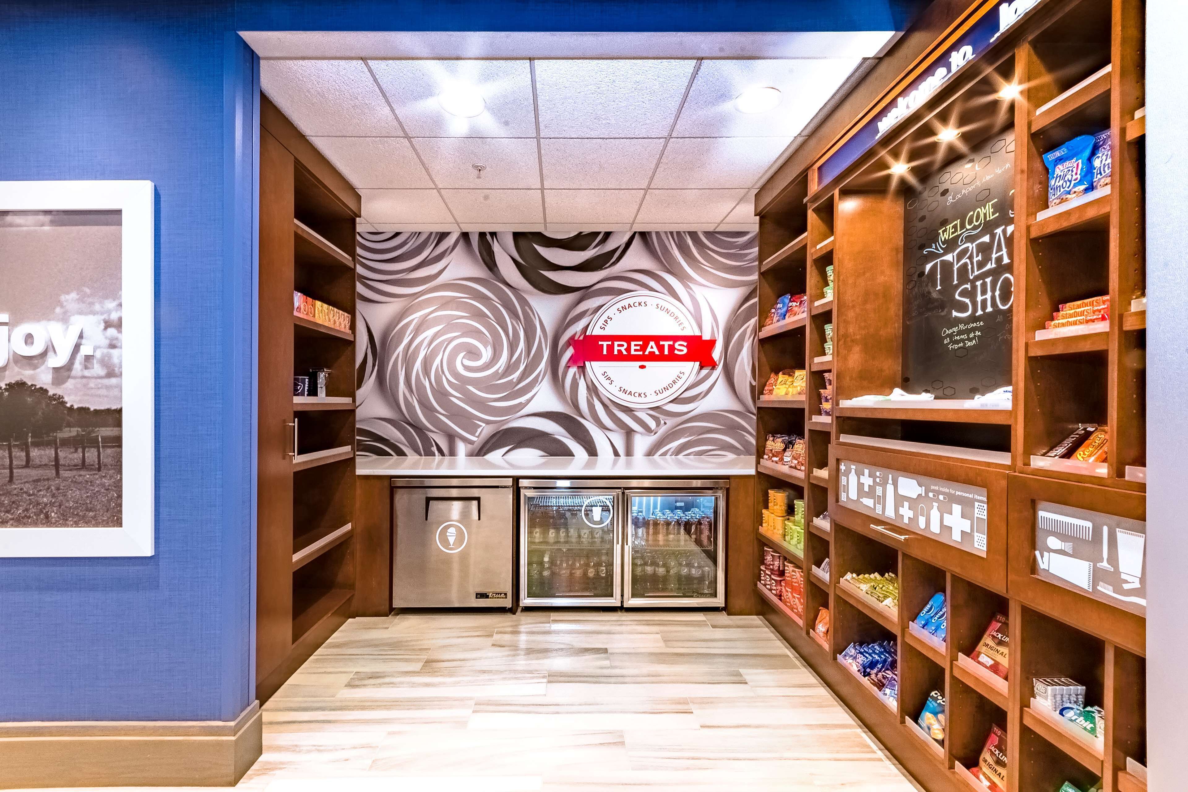 A snack shop with a 'Treats' sign, shelves stocked with snacks, and a refrigerator.
