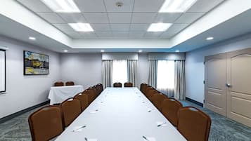 Ett konferensrum med ett långt bord, stolar, en projektorduk och en dörr.
