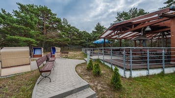 A covered outdoor area with picnic tables, benches, and a wooden pergola.