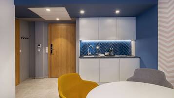A modern kitchen with a blue backsplash, white cabinets, and a wooden door.
