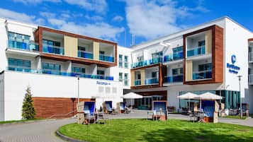 Un hotel moderno con varios balcones, mobiliario exterior y una zona de recepción.