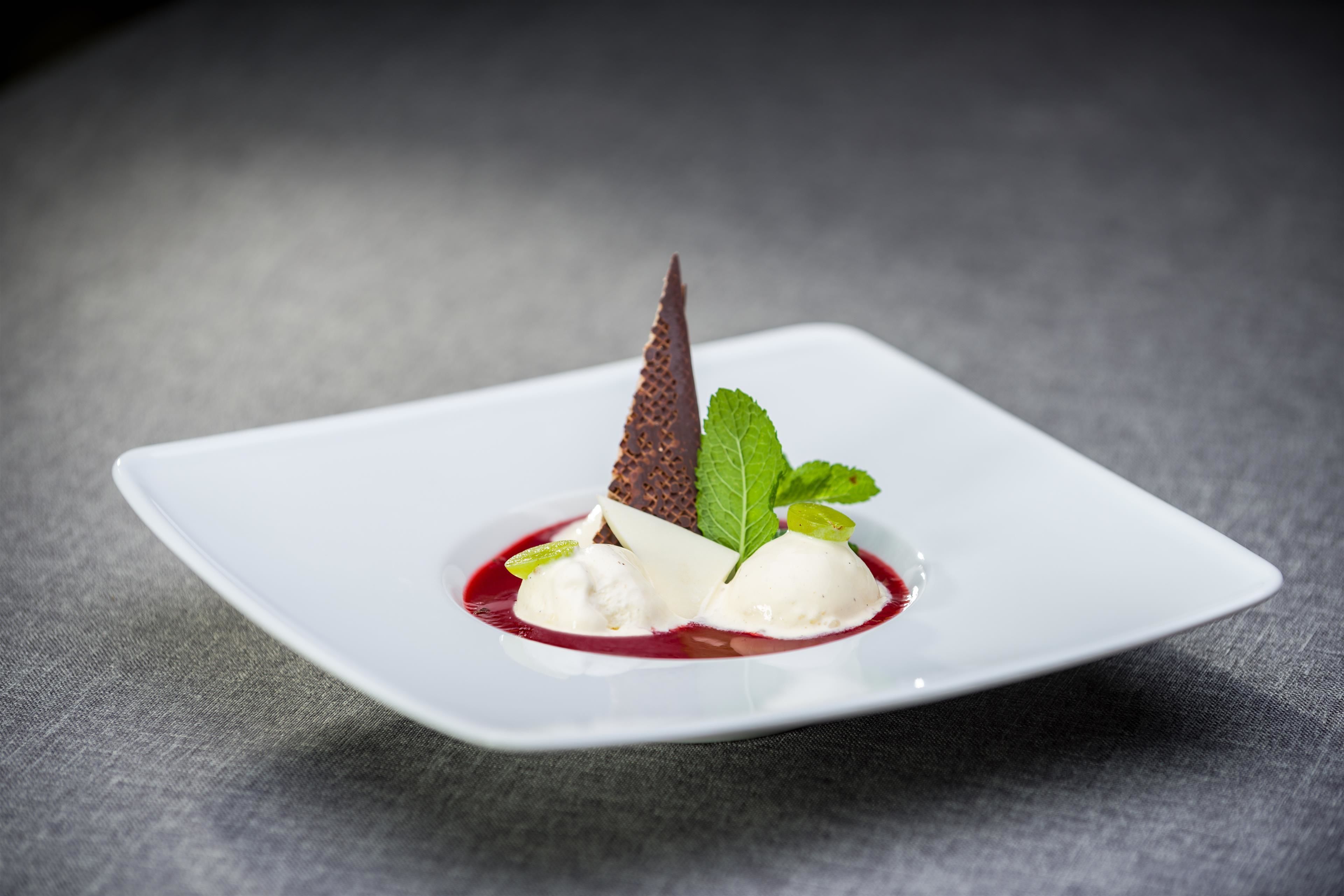 A dessert on a white square plate with a dark background.