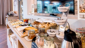 Een buffetopstelling met diverse gerechten, een koffiezetapparaat en een televisie op de achtergrond.