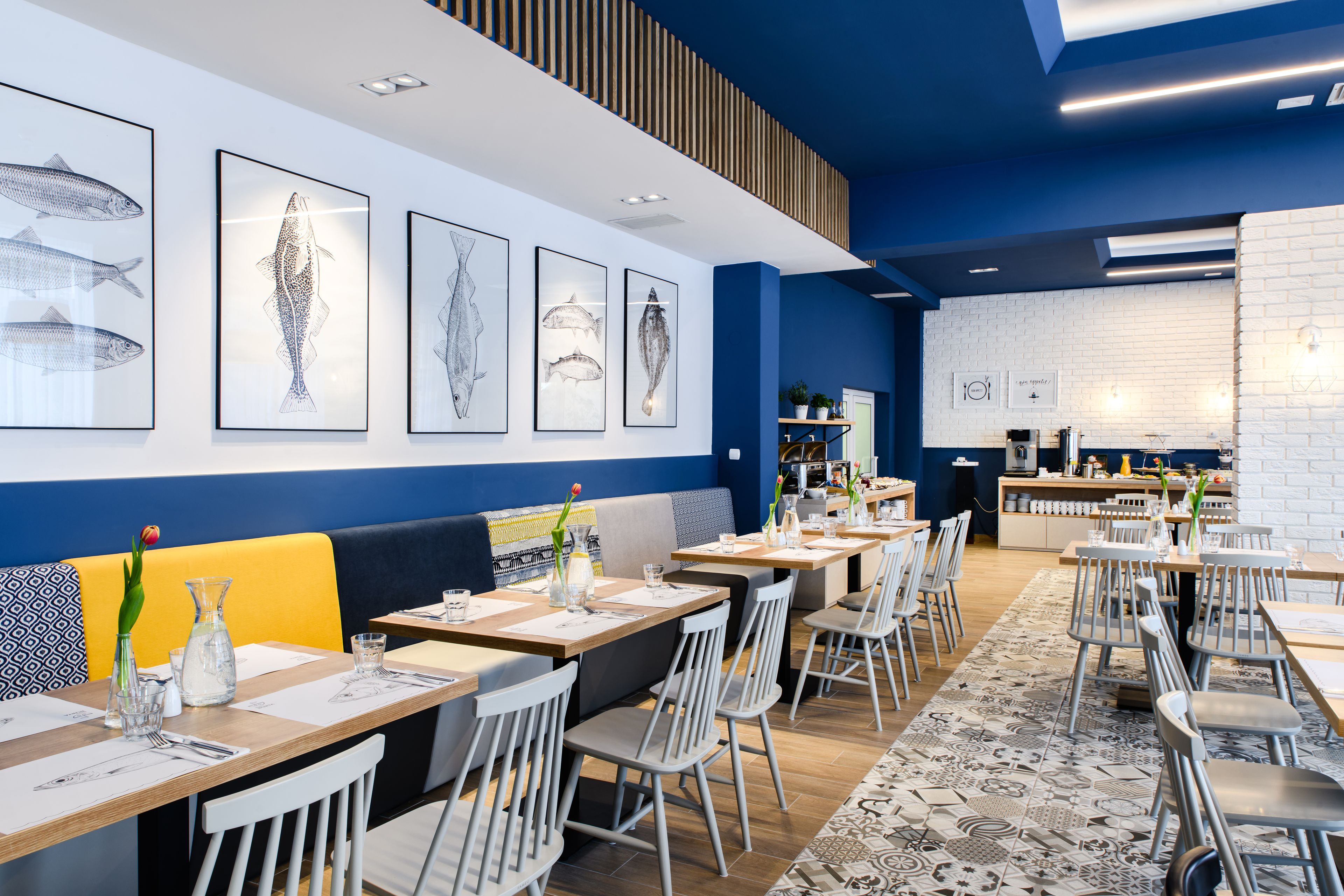 A modern restaurant with wooden tables, white chairs, and blue walls.